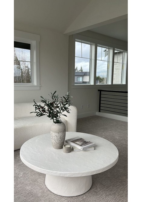  Τραπεζάκι σαλονιού με τεχνική τσιμέντου, στρογγυλό με στρογγυλεμένη βάση σε λευκό χρώμα, σε μοντέρνο καθιστικό οικίας.